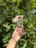 Clear acrylic bookmark with white ghosts, pink flowers, and blush ribbon held outdoors