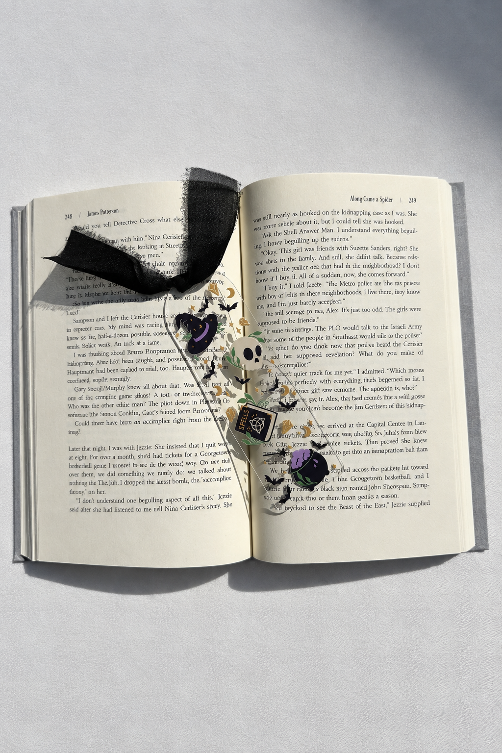 Spells and potions acrylic bookmark resting on an open book with smooth white fabric backdrop