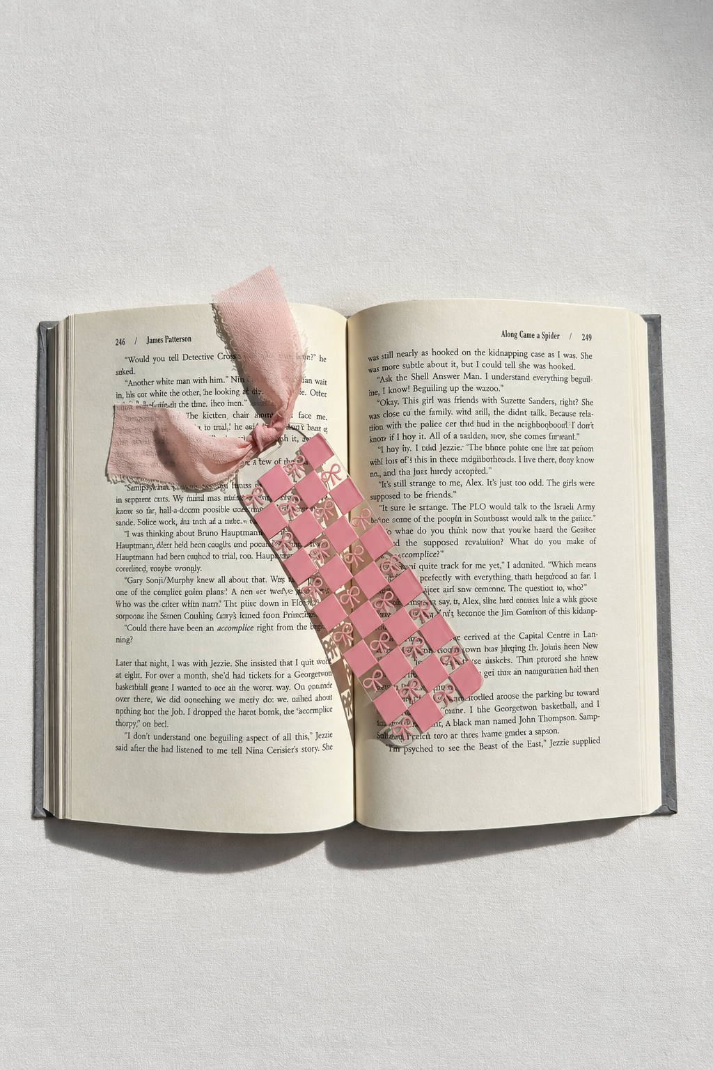 Pink checkerboard and bows acrylic bookmark on an open book with smooth white fabric